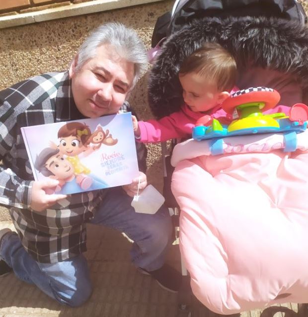 A baby girl named Rocio with her father reading a personalized book by Hooray Heroes.