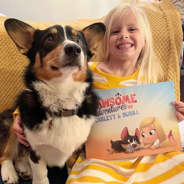 A little girl and her dog with a Hooray Heroes personalized book for dogs.
