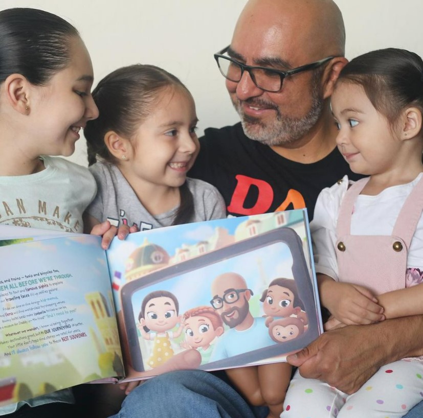 A father and three kids with a personalized book from Hooray Heroes.