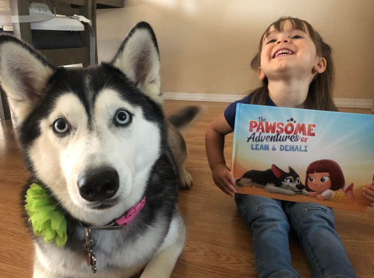 A little girl and her dog with a personalized book for pets and kids from Hooray Heroes.