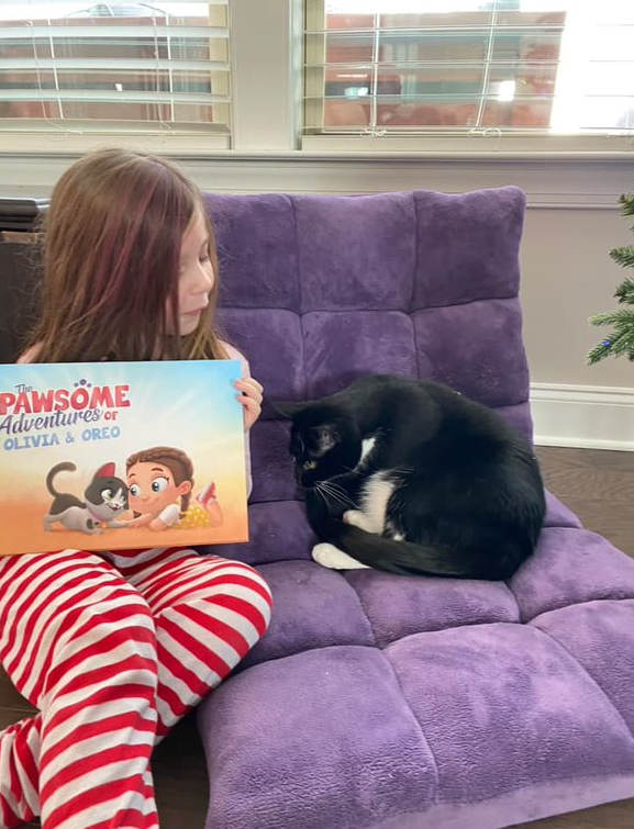 A little girl and her cat with a personalized book for pets and kids from Hooray Heroes.
