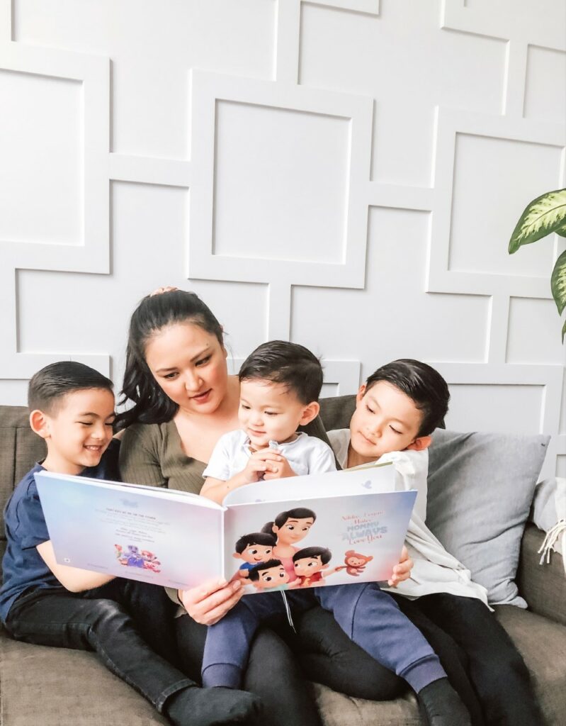 A mom reading a personalized book to her three kids.