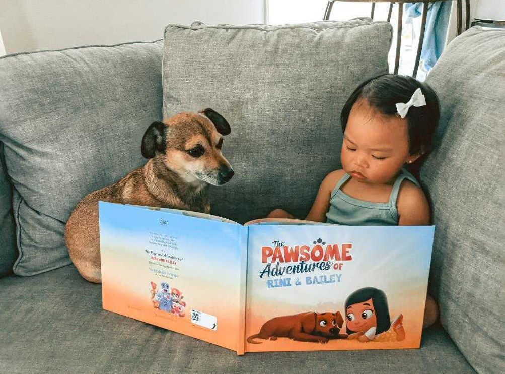 A little girl and her dog with a personalized book for pets and kids from Hooray Heroes.