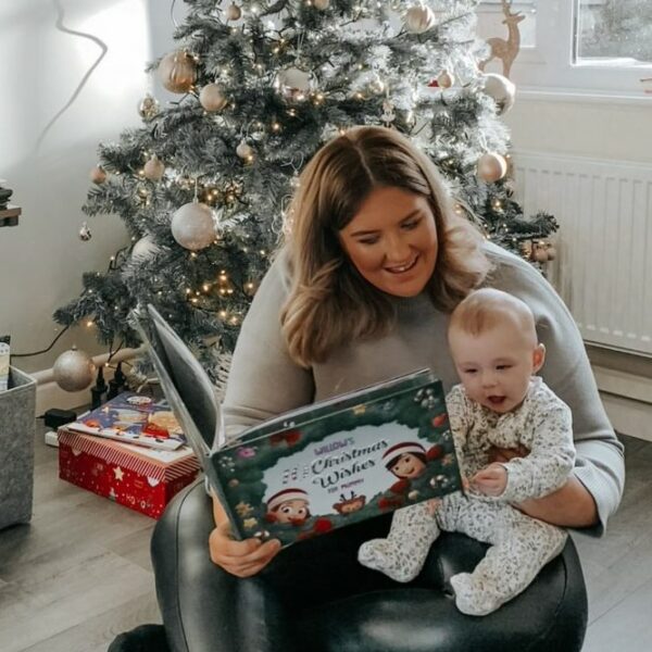 A mother and child read a personalized xmas book together next to a Christmas tree.
