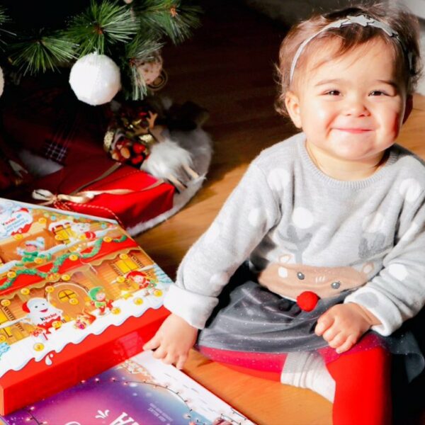 A little girl smiles after receiving a personalized christmas book as an xmas gift.
