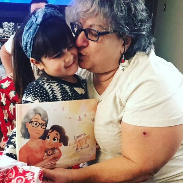 A grandmother kisses her granddaughter who has given her a personalized book for Christmas.