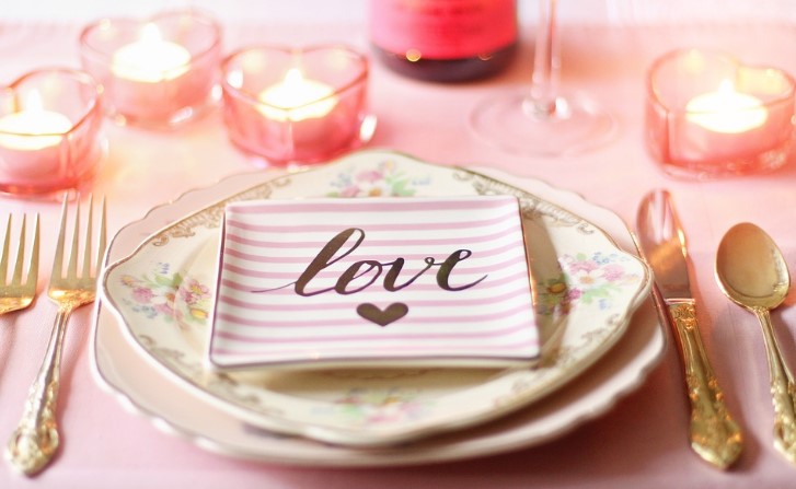 A Valentine place setting at a table with a plate that says "love" in the center.
